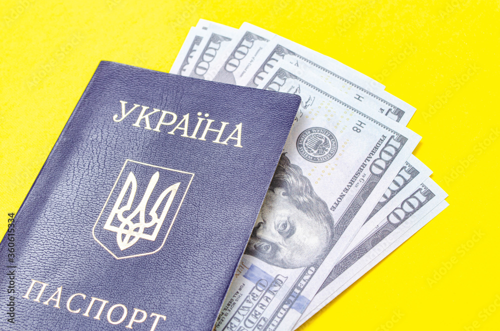 Ukrainian passport on a yellow background. $ 100 dollars are inside the passport at different angles Ukrainian passport on a yellow background. $ 100 dollars are inside the passport at different angles
