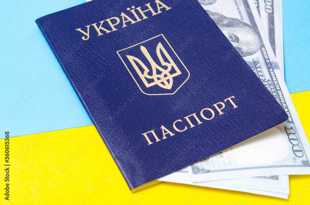 Ukrainian passport on a blue-yellow background. Dollars of 100 dollars are inside the passport at different angles. Packport with dollars on the Ukrainian flag