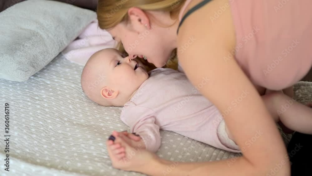 Young happy mother playing hugging and kissing little infant baby, parent with kid at home relaxing on the bed. Family concept Young happy mother playing hugging and kissing little infant baby, parent with kid at home relaxing on the bed. Family concept