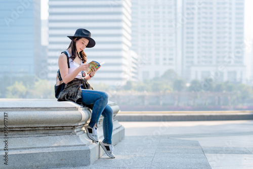 Beautiful asian tourist woman reading travel guide book for searching location of tourist sightseeing.