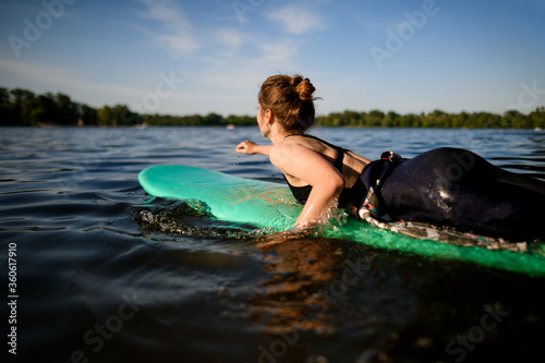 woman lies on surfboard, rows her hands and floats on the river.