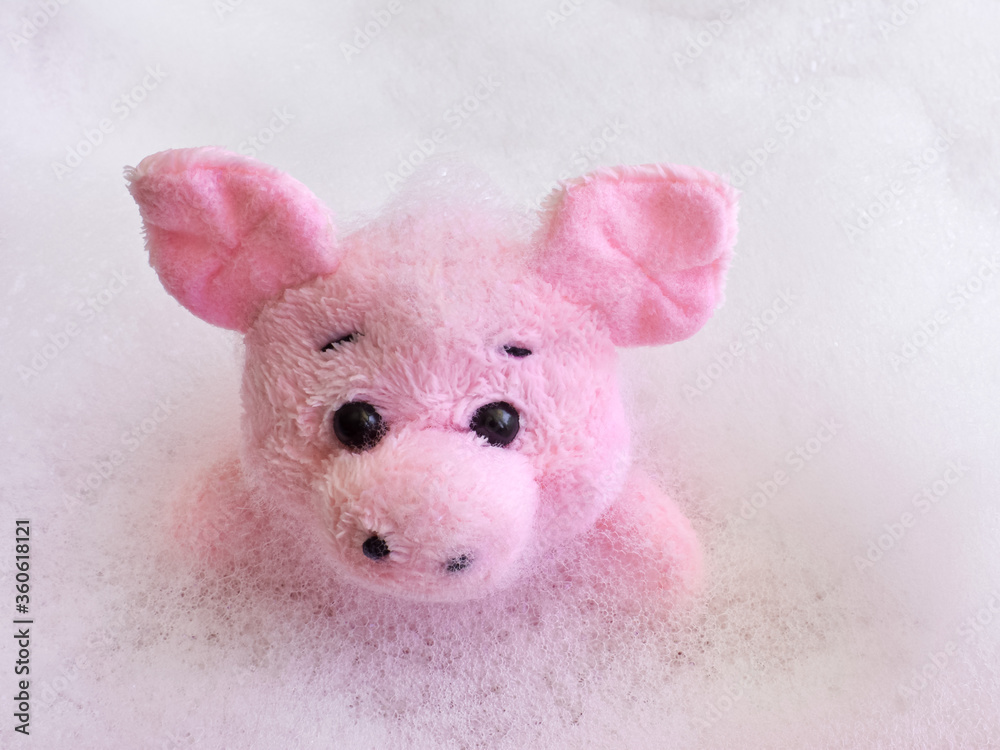 Pink little toy pig in a bath foam. Bathing in the bathroom. Spa. Pink little toy pig in a bath foam. Bathing in the bathroom. Spa.