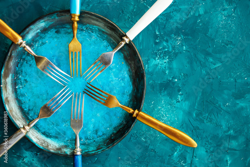 Colored set of kitchen plate with forks on a turquoise blue background. Top view