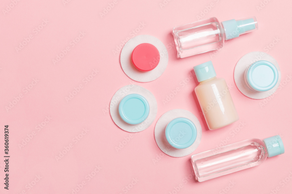 Set of travel size cosmetic bottles on pink background. Flat lay of cream jars. Top view of bodycare style concept Set of travel size cosmetic bottles on pink background. Flat lay of cream jars. Top view of bodycare style concept