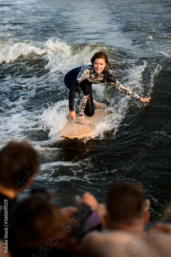 young smiling woman wakesurfer balancing on the wave