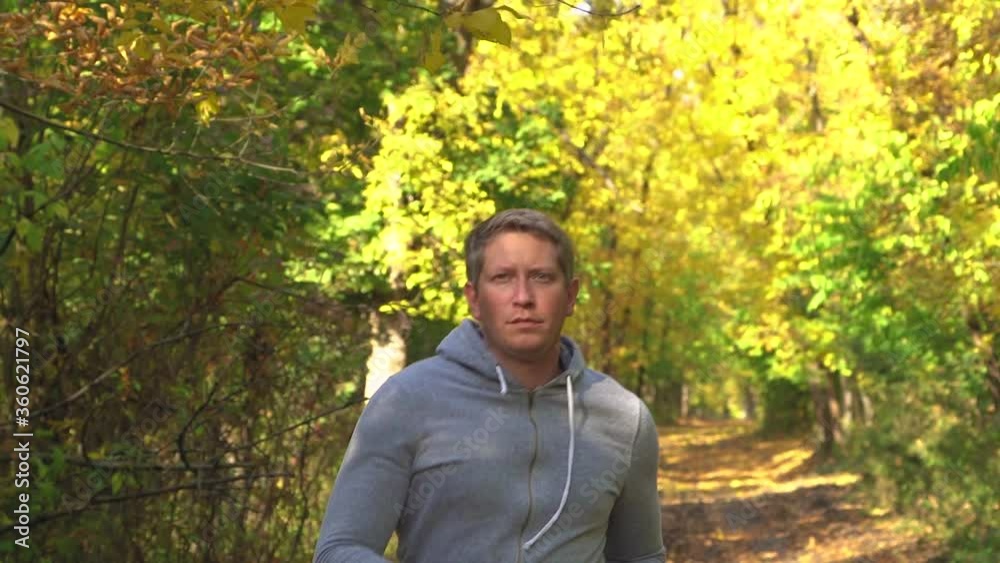 Sport man running in forest .Young man training run in slow motion. Cardio exercise at workout outdoor Sport man running in forest .Young man training run in slow motion. Cardio exercise at workout outdoor
