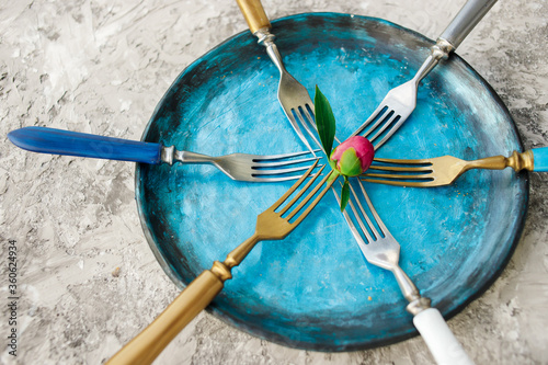 Colored set of kitchen plate with forks on a gray background.