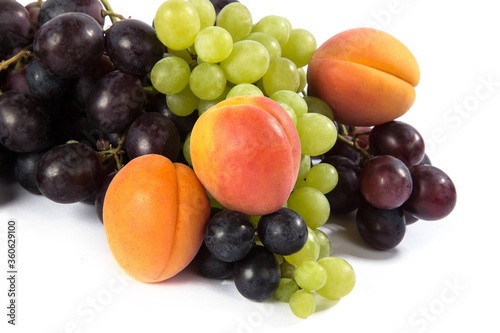 Orange apricots, black and green grapes on a white background.