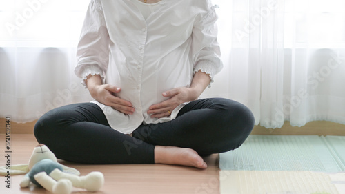 The pregnant woman uses the handle on the belly, She sat by the window there is a beautiful light.