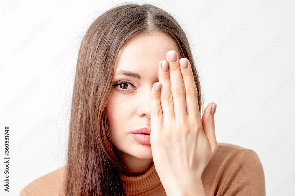Portrait of beautiful young caucasian woman covering her half face with her hand on white background Portrait of beautiful young caucasian woman covering her half face with her hand on white background