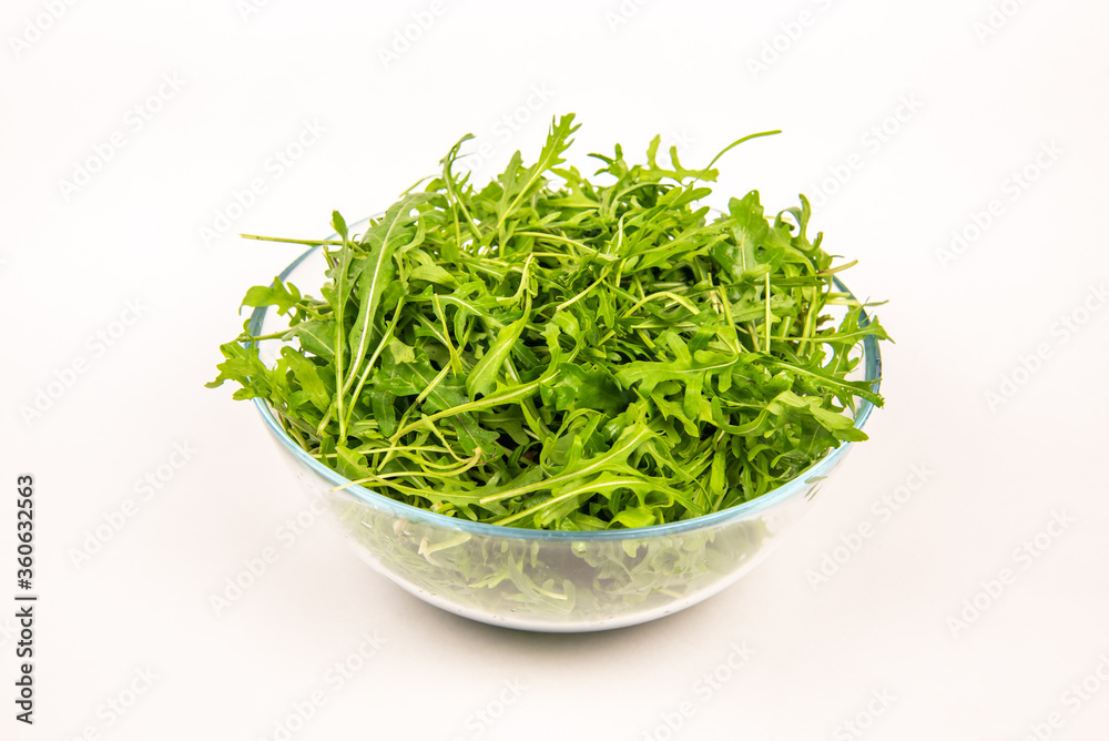 Green arugula leaves in a glass bowl. Healthy eating concept Green arugula leaves in a glass bowl. Healthy eating concept