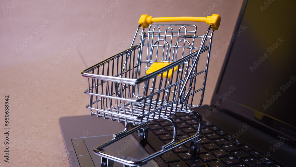 Buy now, Shopaholic on the Internet. Online shopping, shopping cart on laptop keyboard.