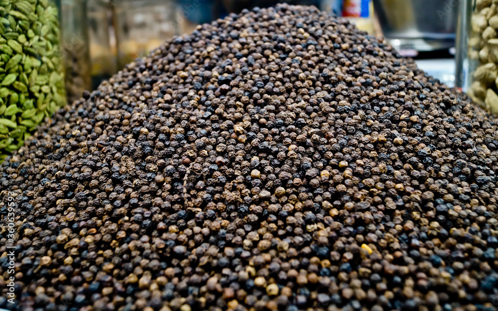 Close up of black peppercorns or kali mari on wooden surface with its extracted herbal beneficial oil. milled black pepper ,Black pepper corns and Black pepper Powder Close up of black peppercorns or kali mari on wooden surface with its extracted herbal beneficial oil. milled black pepper ,Black pepper corns and Black pepper Powder