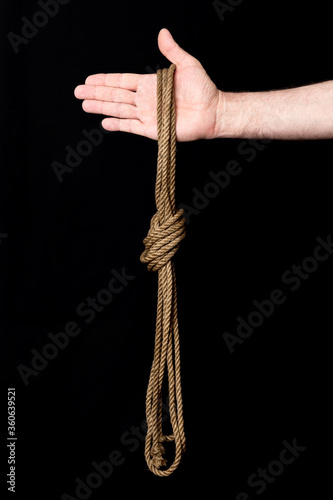 Skein of rope with a knot and male hand on a black background