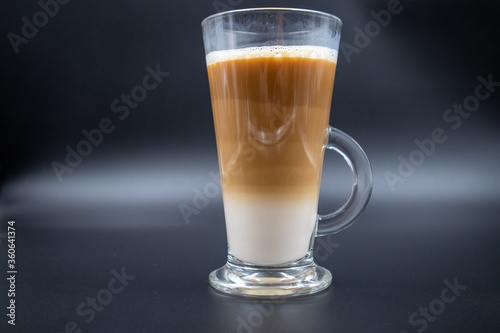 A studio shot of three-layered coffee drink and chocolate chip cookies in black grey background