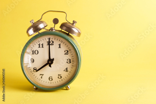 Green alarm clock on the yellow background