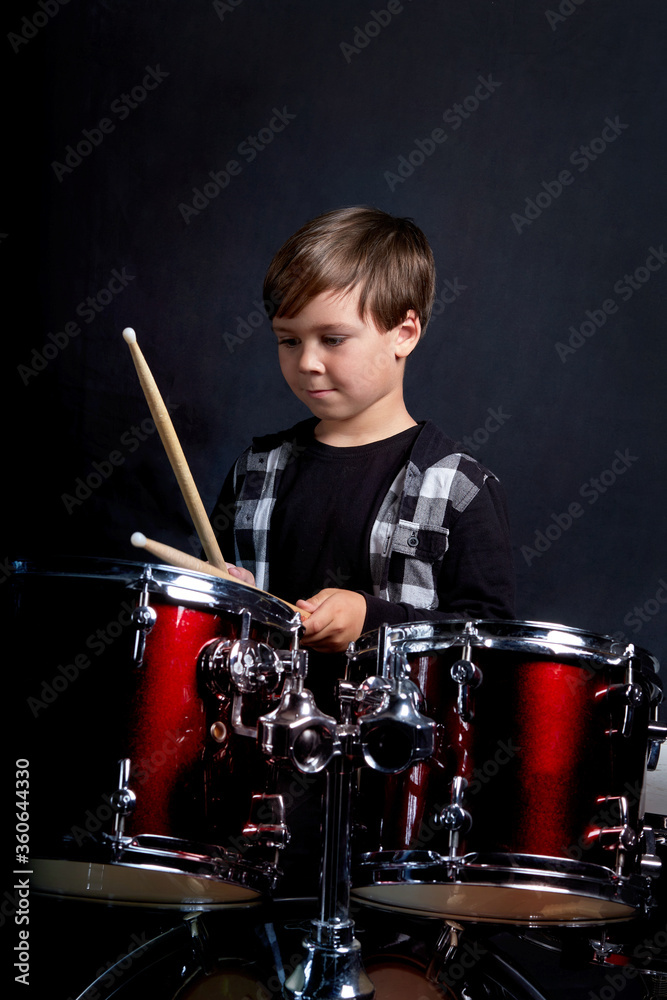 Fototapeta premium Pionowe zdjęcie dziecka z instrumentem muzycznym, perkusją. Ciemnoniebieskie tło