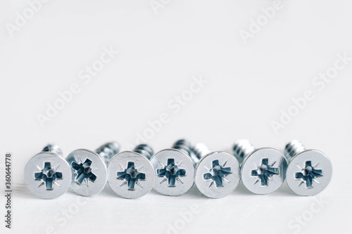 Metal tapping screws for wood on white wooden background. Construction equipment concept. Top view. Copy, empty space for text