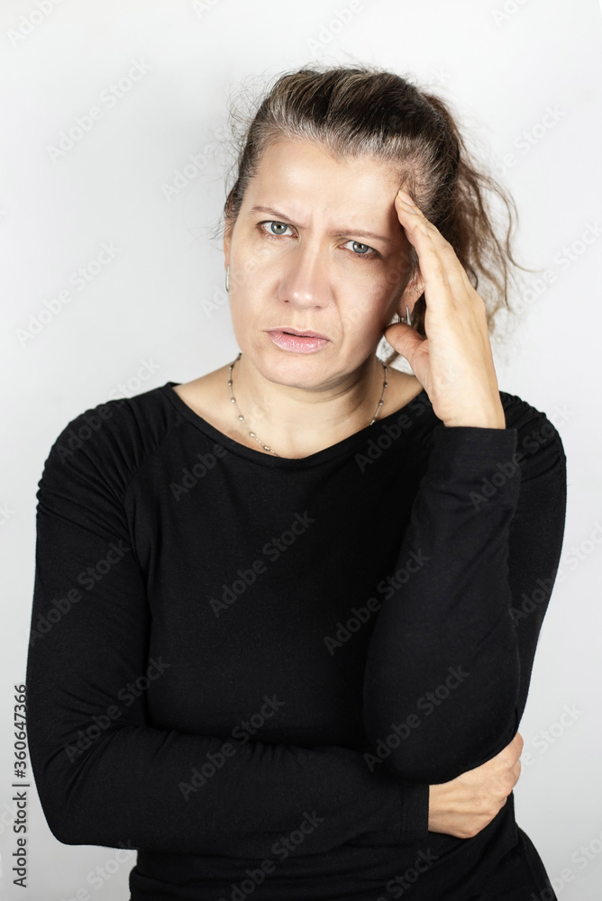 A middle-aged woman is holding her head because she has a severe headache, the weather will probably change, vertical portrait of a woman with a headache A middle-aged woman is holding her head because she has a severe headache, the weather will probably change, vertical portrait of a woman with a headache