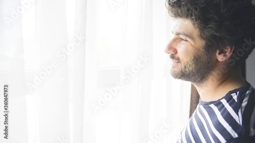 A man is looking on the window and smiles. In the midday.
