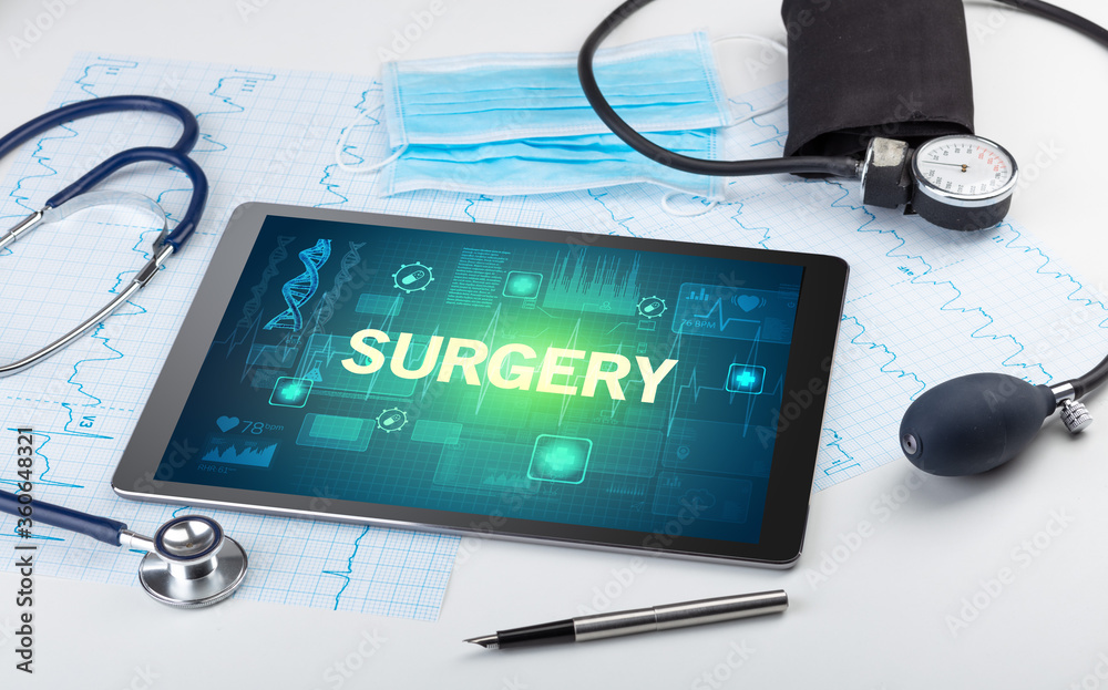 Tablet pc and medical stuff with SURGERY inscription, prevention concept Tablet pc and medical stuff with SURGERY inscription, prevention concept
