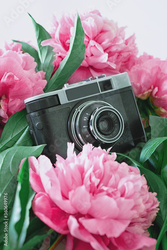 old black camera with pink peonies on the white background