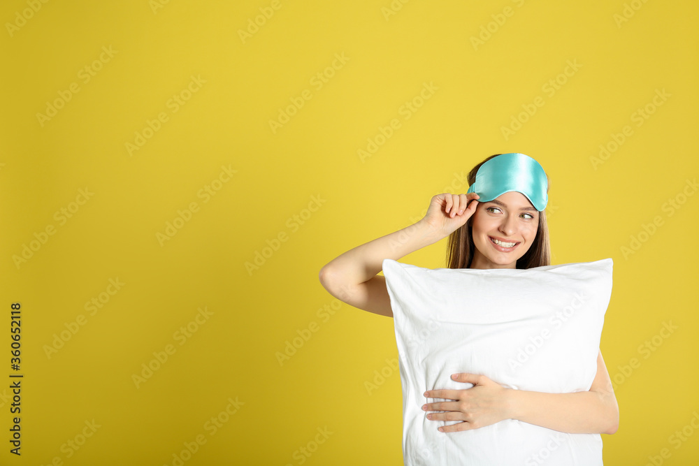 Young woman with pillow and sleep mask on yellow background. Space for text