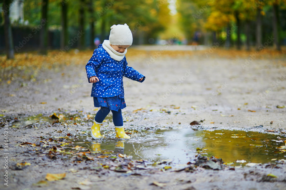 Child wearing yellow rain boots and jumping in puddle on a fall day Child wearing yellow rain boots and jumping in puddle on a fall day