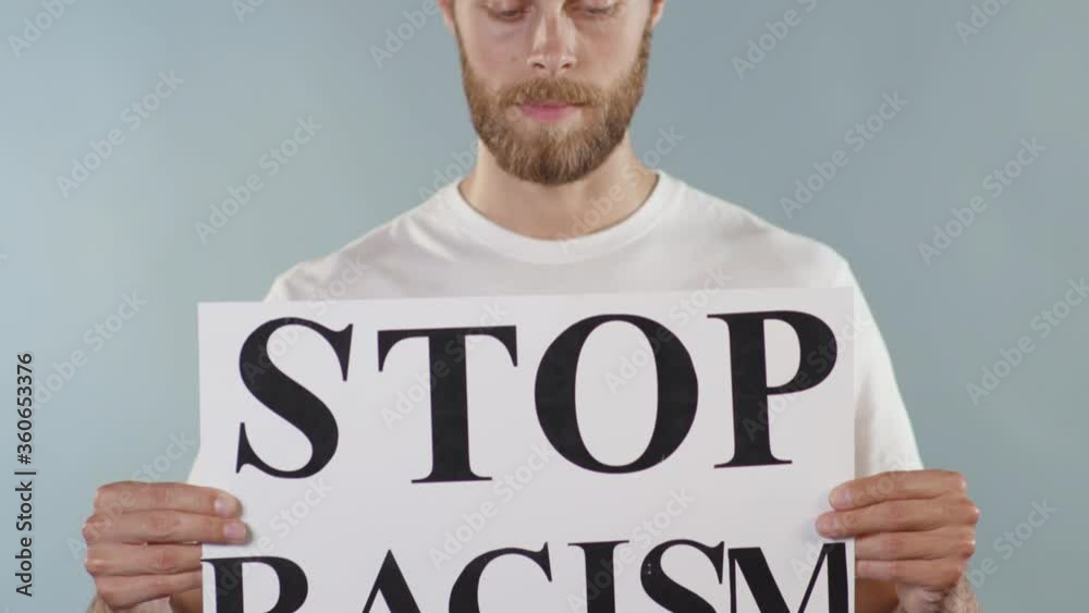 Portrait attractive man hold poster Stop Racism serious racial morality society peace matter human text words can kill torture close up slow motion Portrait attractive man hold poster Stop Racism serious racial morality society peace matter human text words can kill torture close up slow motion