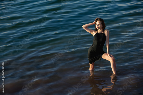 girl in a black dress in blue water posing evening time