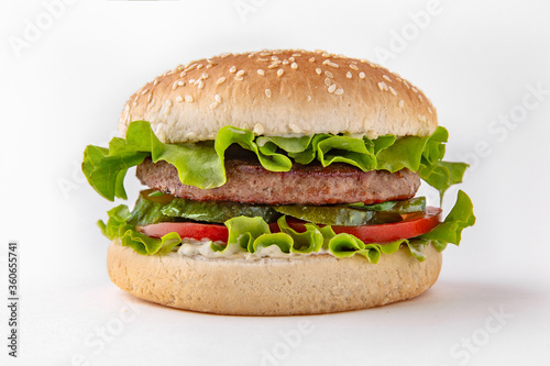 Tasty hearty hamburger with vegetables, cheese and herbs for take away or food delivery isolated on a white background.