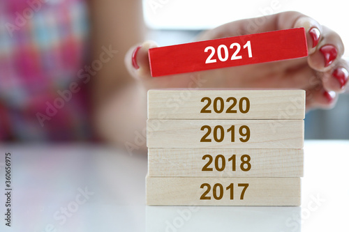 Female hand hold red wooden block with 2021 sign closeup. Chops and changes concept photo