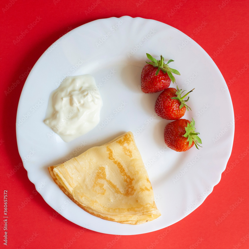 Breakfast, strawberries, pancakes and cream on a white plate Breakfast, strawberries, pancakes and cream on a white plate