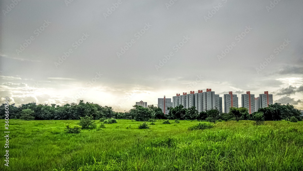 The building on green grassland with blue dark sky background in real estate sale or property investment concept, Buying new home for a family in residential building exterior in Mumbai Pune The building on green grassland with blue dark sky background in real estate sale or property investment concept, Buying new home for a family in residential building exterior in Mumbai Pune