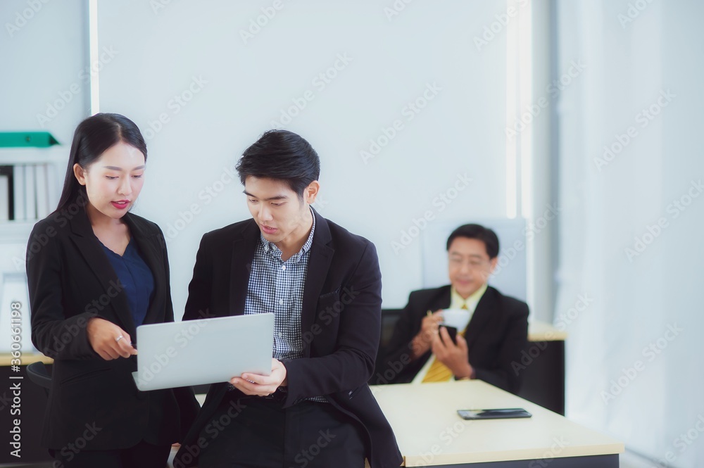 Happy young Asian Business people stand to discussing marketing information In the laptop computer in the office that looks modern, concept of teamwork of colleagues with happiness Happy young Asian Business people stand to discussing marketing information In the laptop computer in the office that looks modern, concept of teamwork of colleagues with happiness