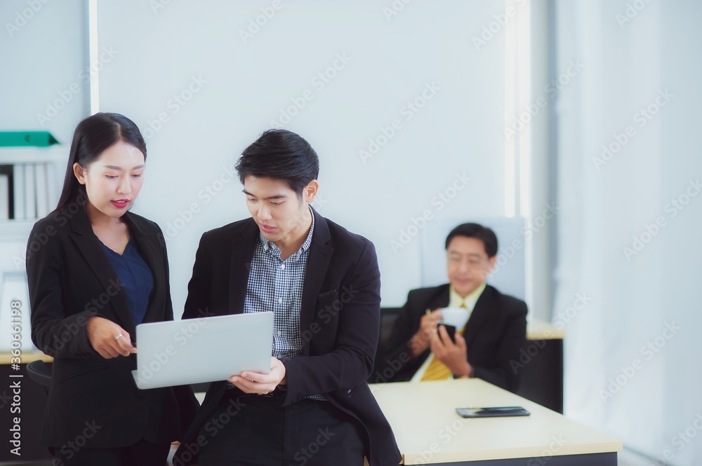 Happy young Asian Business people stand to discussing marketing information In the laptop computer in the office that looks modern, concept of teamwork of colleagues with happiness