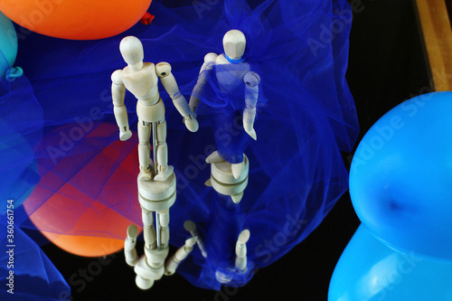 Pair of mannequins from above. She with blue toulle dress walking along a catwalk. Blue background and colorful balloons. photo