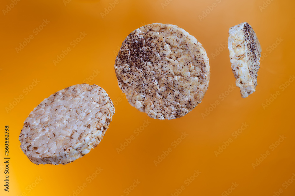 Fototapeta premium Wheat breads fall on orange background. Advertising photo. Close-up