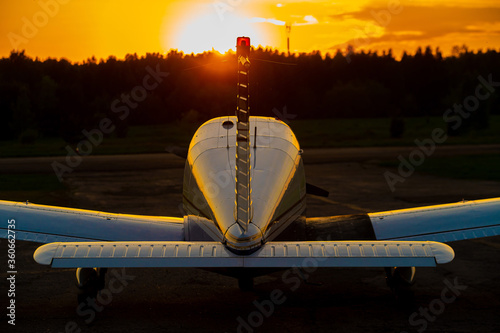 Quadruple aircraft parked at a private airfield. Rear view of a plane with a propeller on a sunset background. photo