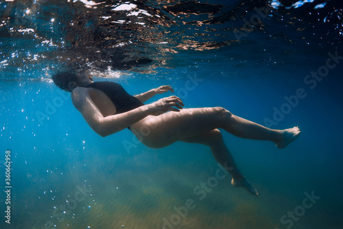 Woman swimming in blue sea. Underwater view in transparent ocean