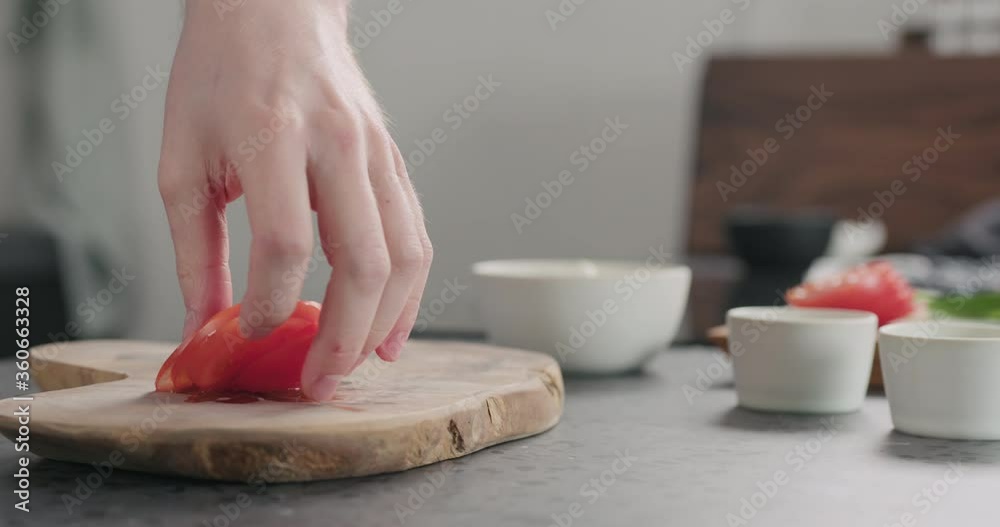 Slow motion dolly shot of man take sliced tomato from olive wood board Slow motion dolly shot of man take sliced tomato from olive wood board