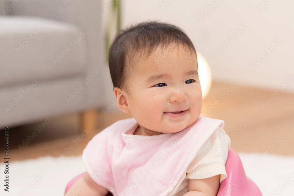 ベビーチェアにお座りする笑顔の赤ちゃん