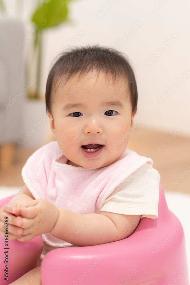 ベビーチェアにお座りする笑顔の赤ちゃん