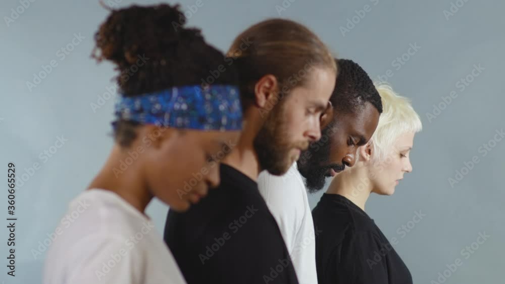 Side shot of group of people of different races lowered their heads ...
