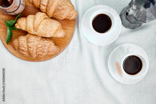 Two coffee cups and Italian coffee maker with croissant over table at home morning breakfast rituals concept, lifestyle food background..