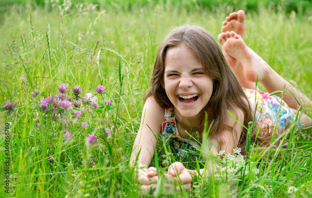 girl 10 years old in a dress lying on the grass in a clearing and laughing girl 10 years old in a dress lying on the grass in a clearing and laughing