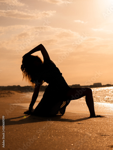 Fit woman doing yoga stretching exercise outdoor near sea. sea and sunrise or sunset background training asians. Silhouette of woman in yoga poses 