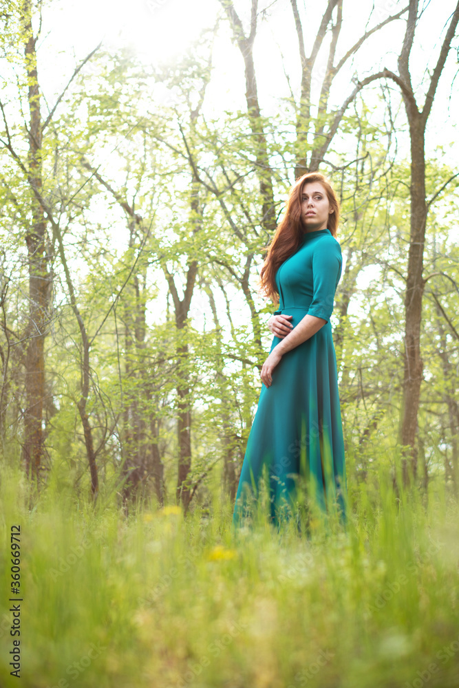 Beautiful woman in elegant dress stands in forest on background of green trees. Natural beauty concept. Beautiful woman in elegant dress stands in forest on background of green trees. Natural beauty concept.