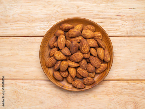 almonds in wood plate on pine wood table .
