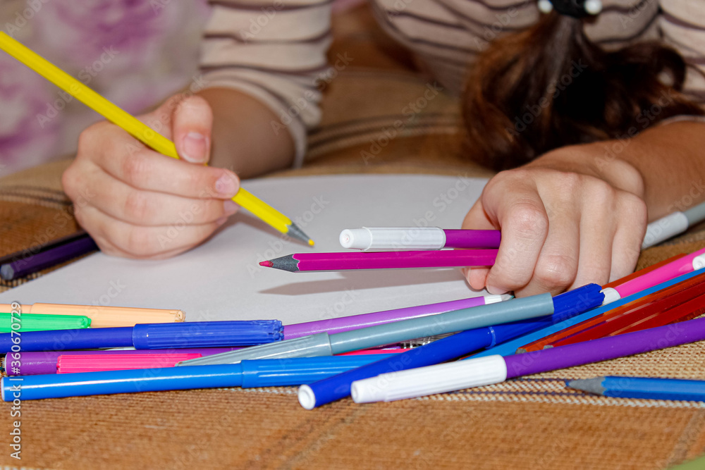 The girl is at home on the couch and draws with colored pencils and markers. The girl is at home on the couch and draws with colored pencils and markers.